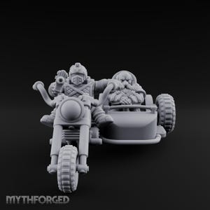 May include: A grey miniature motorcycle with a sidecar, featuring two figures. The driver wears a helmet and armoured clothing, while the passenger has a long beard. The motorcycle has large tyres and the text "MYTHFORGED" is at the bottom.