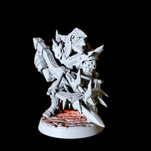 May include: A white plastic miniature figurine of a goblin warrior holding a spiked weapon. The goblin is wearing armour and a helmet. The figurine is standing on a round base.