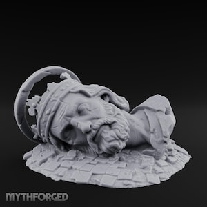 Puede incluir: Una escultura en miniatura de resina gris de la cabeza de un rey caído que lleva una corona con un halo circular, descansando sobre una base de baldosas de piedra rotas. La figura presenta una barba y rasgos faciales detallados, con el texto MYTHFORGED.