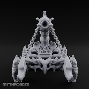 May include: A grey miniature siege engine featuring a central cannon-like structure supported by chains, mounted on a frame constructed from bone-like elements with wheels on the sides. A pile of small skulls sits on the platform. Text reads MYTHFORGED.