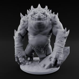 May include: A gray, 3D-printed fantasy creature figurine. The muscular figure has a large head with a toothy grin, spiky protrusions, and a rope belt. The creature is posed with one hand on a rock and the other on the ground.