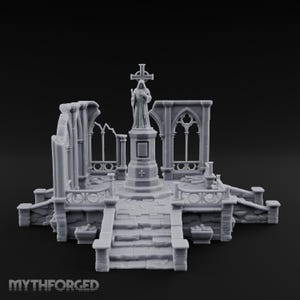 Puede incluir: Un diorama en miniatura de color gris claro de una catedral de piedra en ruinas con una figura encapuchada central sobre un pedestal bajo una cruz. La estructura incluye marcos de ventanas arqueados, escaleras de piedra y barandillas.