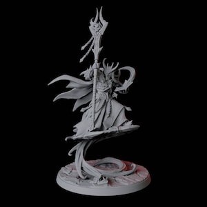 Puede incluir: Una figura miniatura pintada en gris de un mago con cuernos, que lleva una túnica y sostiene un bastón. El mago está de pie sobre una base giratoria que se asemeja a la cola de un dragón.