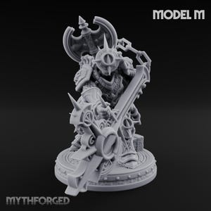 Op de afbeelding: Een grijze miniatuurfiguur van een krijger in gedetailleerd harnas, met een groot zwaard en een bijlachtig schild. Het beeldje staat op een cirkelvormige basis. De tekst "MODEL M" en "MYTHFORGED" zijn zichtbaar.