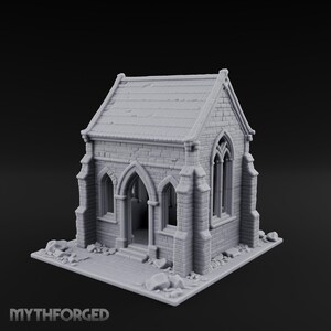 Puede incluir: Una miniatura de edificio gris sin pintar con un exterior de textura de piedra, techo a dos aguas, ventanas arqueadas y una puerta central arqueada. La estructura se asienta sobre una base cuadrada con escombros de piedra y el texto MYTHFORGED.