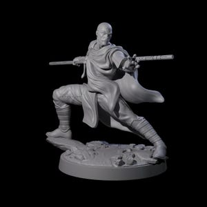 May include: A grey figurine of a bald figure in a dynamic pose, holding a staff. The figure is wearing a draped garment and leggings, posed on a rocky base. The background is black.