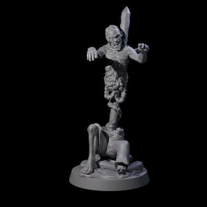 May include: A grey 3D-printed figurine of a zombie impaled on a wooden stake. The zombie's upper body is intact, with exposed intestines and a menacing expression. The lower body is severed, resting on a rocky base.
