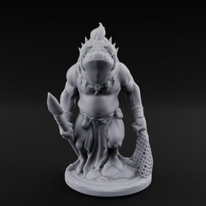 Peut inclure: Figurine de créature fantastique grise imprimée en 3D. La figurine humanoïde musclée a une tête de poisson, tenant une lance et un filet. Elle porte un pagne et un collier de dents. La figurine est sur une base circulaire.