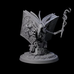 Könnte beinhalten: Graue, 3D-gedruckte Miniatur einer skelettartigen Figur in einer Kapuzenrobe, die einen Stab hält und vor einem offenen Buch steht. Das Buch hat verzierte Designs. Die Figur steht auf einem kreisförmigen Sockel.