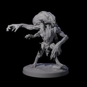 Può includere: Scultura grigia tridimensionale di una creatura umanoide con una grande testa e arti allungati. La creatura ha un aspetto scheletrico ed è posata su una base circolare, con un braccio teso.