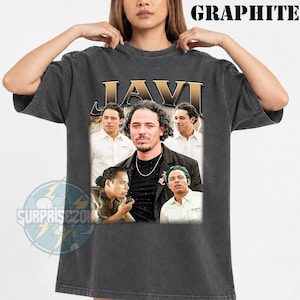 Può includere: Una t-shirt a maniche corte grigio antracite con il testo JAVI in grandi lettere dorate sulla parte superiore. La grafica include quattro ritratti fotografici di un uomo in varie pose e abiti, con la parola GRAPHITE stampata in alto a destra.