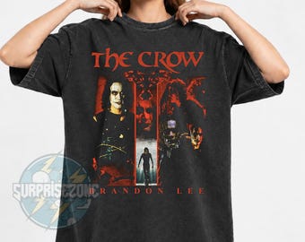 May include: A mineral wash black t-shirt featuring a graphic print from The Crow movie. The design includes the text The Crow and Brandon Lee, with imagery of the main character in a dark, red-toned setting. The shirt has short sleeves.
