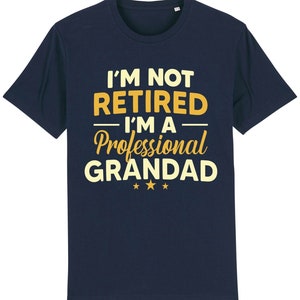 May include: Navy blue t-shirt with the text "I'm not retired - I'm a professional Grandad" in yellow. The text is in a vintage style font.