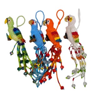 May include: Four beaded parrot ornaments in green, blue, orange, and white. Each bird has a loop for hanging and a beaded tail. The parrots are decorated with colorful beads and have yellow beaks. These ornaments are suitable for home decor.
