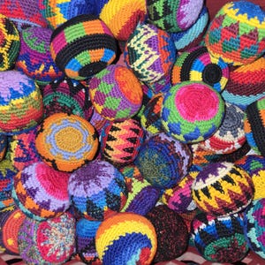 May include: A collection of colourful crocheted balls with various geometric patterns. The balls are made with different coloured yarns, including red, blue, green, yellow, and purple.