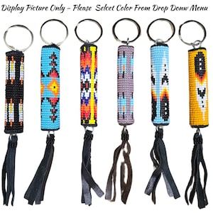 May include: Six cylindrical keychains featuring intricate beadwork in various geometric patterns and colors, including black, blue, orange, yellow, and grey. Each keychain has a metal ring at the top and a black leather fringe tassel at the bottom.