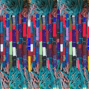 May include: A close-up of a collection of colourful woven friendship bracelets with tassels. The bracelets are made with various colours of thread, including red, blue, green, yellow, and white.