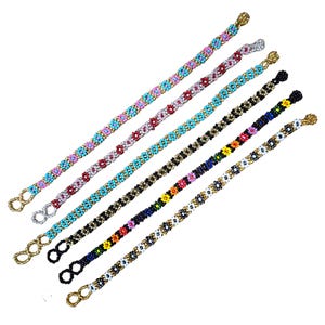 May include: Six colorful beaded bracelets with floral patterns. Each bracelet has a gold clasp.