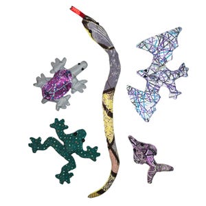May include: A collection of handmade fabric toys, including a long snake with a red tongue, a turtle with a glittery purple shell, a green frog with white polka dots, a pterodactyl, and a fish. The toys are made of various patterned fabrics.
