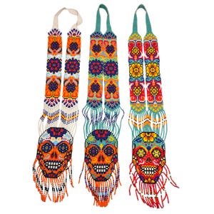 May include: Three beaded Day of the Dead skull necklaces. Each necklace features a colorful skull pendant with intricate beadwork in orange, blue, yellow, and red. The necklaces have long, beaded straps with floral patterns.