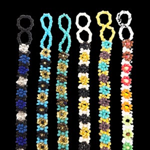 May include: A collection of beaded accessories in various colors, including blue, turquoise, white, yellow, and brown. Each piece features a loop at the top and a floral pattern along the length, set against a black background.