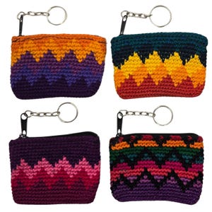 May include: Four handmade crochet coin purses with keychains. Each purse features a zig-zag pattern in various color combinations: orange, purple, and yellow; teal, yellow, and red; purple and pink; and green, pink, and orange.