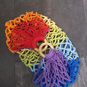 May include: A rainbow crochet bag with wooden handles. The bag is made of a variety of colors, including red, orange, yellow, green, blue, and purple.
