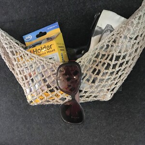 May include: A beige crocheted net bag with a white pouch, sunglasses, and a yellow package labeled "iHolder Device Mount" inside.