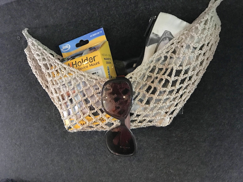 May include: A beige crocheted net bag with a white pouch, sunglasses, and a yellow package labeled "iHolder Device Mount" inside.