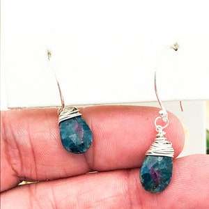 Puede incluir: Un par de pendientes de alambre plateado envueltos con piedras preciosas azules y verdes en forma de lágrima.