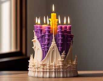 May include: A decorative candle shaped like a castle, with a cream-colored base and purple and yellow towers. Lit candles are on top. The candle sits on a wooden surface.