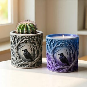 Könnte beinhalten: Zwei dekorative Behälter. Einer enthält einen Kaktus, der andere eine brennende Kerze. Beide zeigen einen Raben, der auf einem Ast in einem waldgesäumten Walddesign sitzt. Der Kerzenbehälter hat blaue und violette Farbtöne.