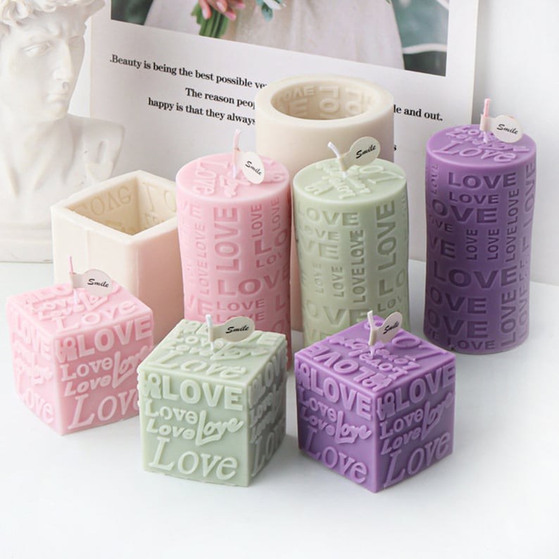 May include: Six candles in various shapes and sizes, all with the word "Love" embossed on them. The candles are in pink, green, and purple.