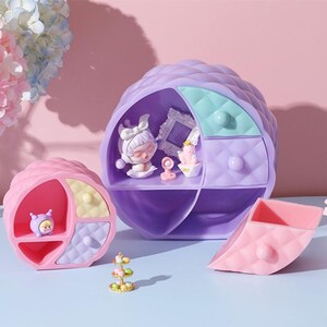May include: A set of three pastel-colored, quilted, round storage boxes with a decorative design. The boxes have different compartments and are perfect for organizing small items.