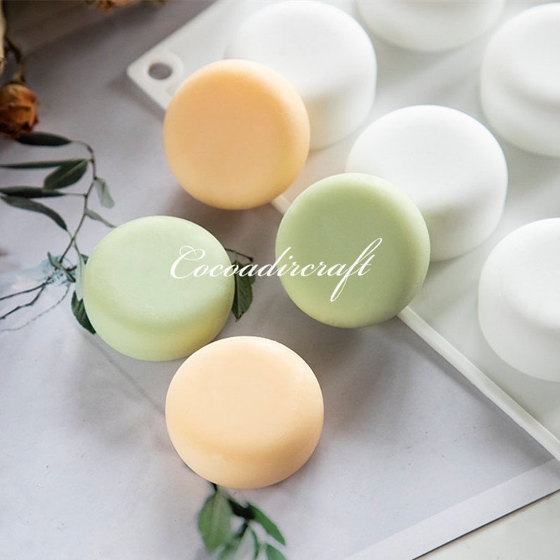 May include: Four round silicone molds for making soap or other crafts. The molds are in a white silicone tray. Three finished soap rounds are shown in the colors green, yellow, and orange.
