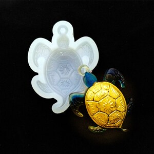 Peut inclure: Un moule en silicone blanc en forme de tortue avec un charme de tortue doré et bleu.