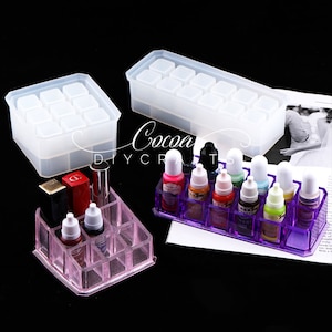 May include: Two clear silicone molds for making resin crafts. One mold is rectangular and has 12 square compartments. The other mold is square and has 9 square compartments. A purple plastic organizer with 12 compartments holds small bottles of liquid.
