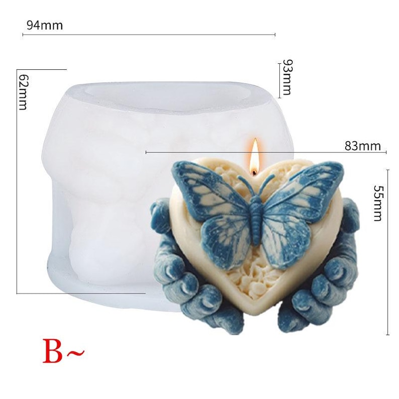 May include: A heart-shaped candle with a blue butterfly design, held by two blue hands. The candle measures 3.3 inches wide and 2.2 inches high. The candle is lit with a small flame. The mold is 3.7 inches wide and 2.4 inches high.