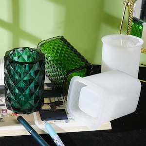 May include: Three glass containers for holding pens or other small items. Two are green with a diamond pattern and one is white with a smooth surface.