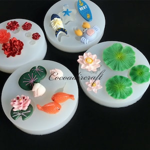 May include: Four silicone molds for making various shapes, including flowers, fish, lily pads, and a crab. The molds are white and have a variety of colors in the shapes.