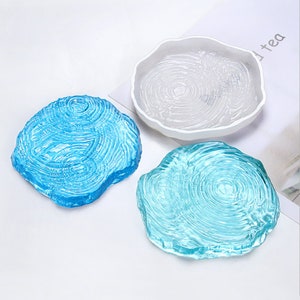 Può includere: Tre stampi in resina per l'artigianato, due sono blu e uno è bianco. Gli stampi hanno la forma di anelli di albero e hanno una superficie testurizzata.