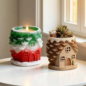 May include: Two house-shaped ornaments. One is a candle with a green, white, and red exterior, resembling a snowy roof. The other is a planter with a succulent and a chimney. Both are on a white surface.
