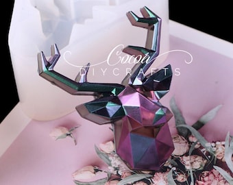May include: A geometric deer head mold made of clear silicone. The mold is shown with a purple and green iridescent resin cast of the deer head.