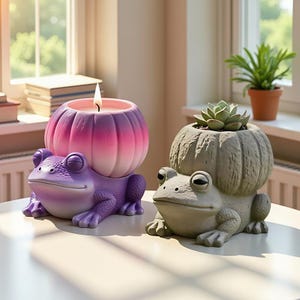 May include: Two frog-shaped decorative items. One is a purple candle holder with a lit candle, the other is a gray planter with a succulent. Both are on a white surface, near a window with a plant.