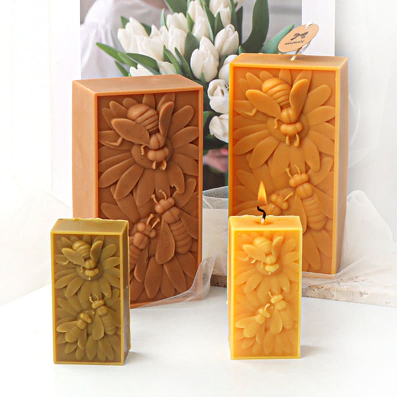 May include: Three rectangular beeswax candles with a honeybee and sunflower design. The candles are in different sizes and shades of yellow and brown.