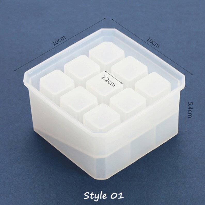 May include: White silicone mold with nine square compartments for making resin crafts. The mold measures 10 cm x 10 cm x 5.4 cm and each square is 2.2 cm. The mold is labeled "Style 01".