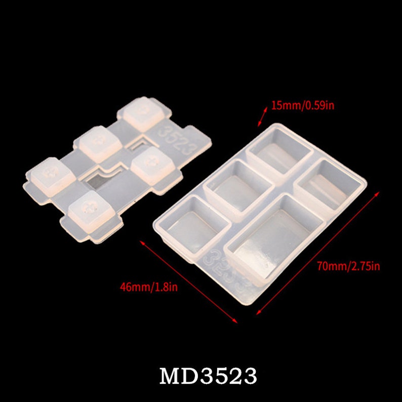 May include: A clear silicone mold for making resin keycaps. The mold is 2.75 inches long and 1.8 inches wide. It has six rectangular cavities for making keycaps. The mold is labeled "MD3523".