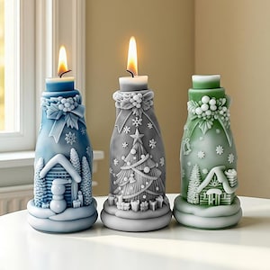 May include: Three lit Christmas-themed candles in blue, gray, and green. Each candle features a unique design, including a snowman, Christmas tree, and house. The candles are on a white surface, with a window in the background.