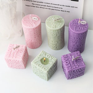 May include: Six candles in various shapes and sizes, all with the word "Love" embossed on them. The candles are in pink, green, and purple.