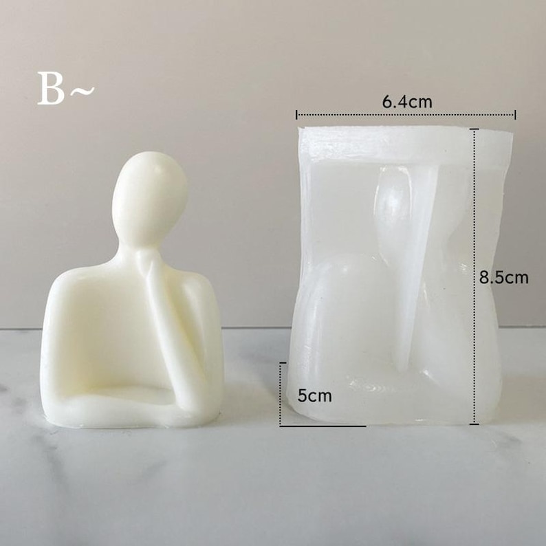May include: A cream-colored, abstract human figure sculpture and a clear silicone mold. The sculpture is in a seated pose with a hand on the chin. The mold measures 6.4cm wide, 8.5cm tall, and 5cm deep.